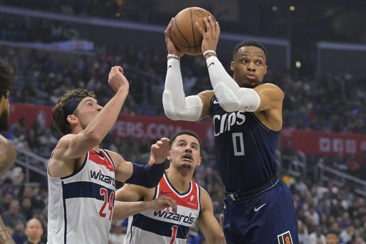 Mar 1, 2024; Los Angeles, California, USA; Los Angeles Clippers guard Russell Westbrook (0) passes the ball as he is defended by Washington Wizards forward Corey Kispert (24) and guard Johnny Davis (1) in the first half at Crypto.com Arena.