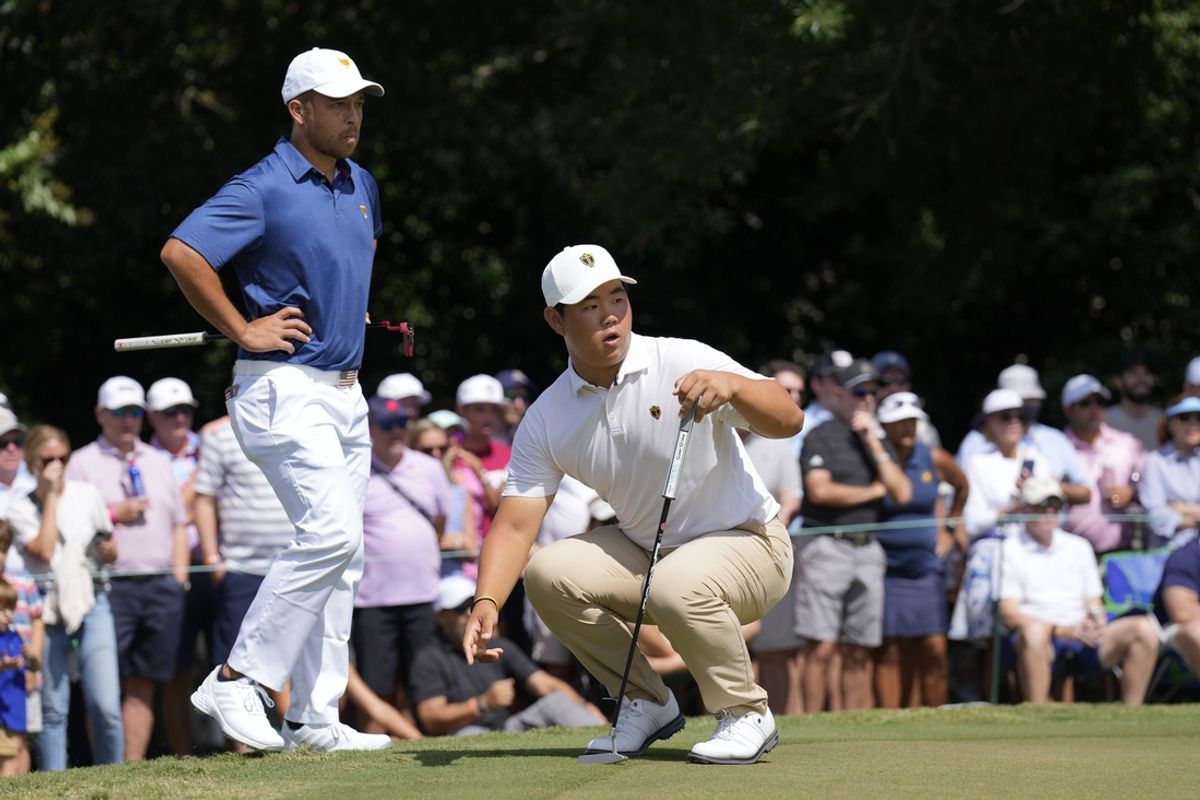 Sep 24, 2022; Charlotte, North Carolina, USA; International Team golfer Tom Kim (right) reacts to his putt in front of Team USA golfer Xander Schauffele (left) on the third hole during the four-ball match play of the Presidents Cup golf tournament at Quail Hollow Club. Mandatory Credit: Jim Dedmon-Imagn Images