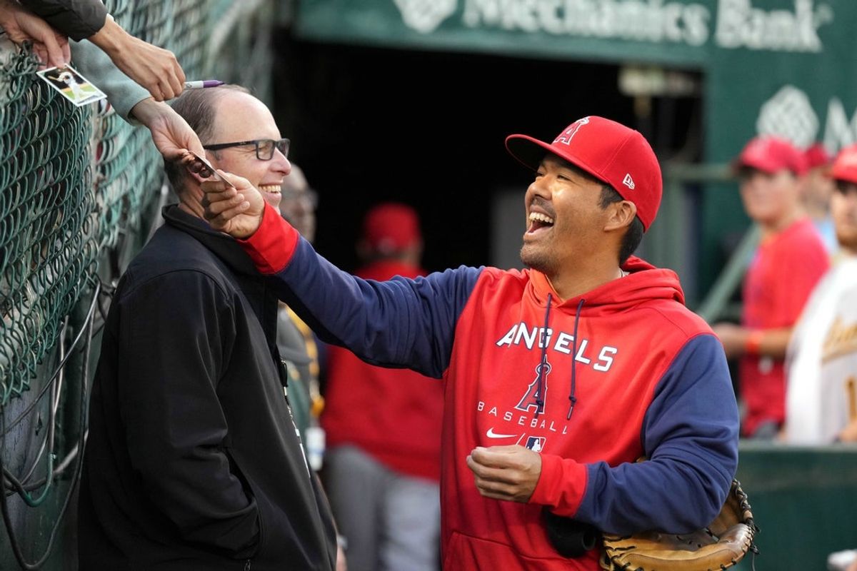 Oct 3, 2022; Oakland, California, USA; Los Angeles Angels catcher Kurt Suzuki (24) signs an autograph before the game against the Oakland Athletics at RingCentral Coliseum. Mandatory Credit: Darren Yamashita-Imagn Images