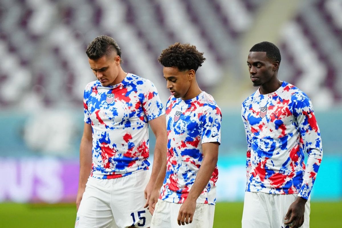 Dec 3, 2022; Al Rayyan, Qatar; United States of America defender Aaron Long (15) and midfielder Tyler Adams (center) and forward Timothy Weah (right) walk on the field after losing a round of sixteen match against the Netherlands in the 2022 FIFA World Cup at Khalifa International Stadium. Mandatory Credit: Danielle Parhizkaran-Imagn Images