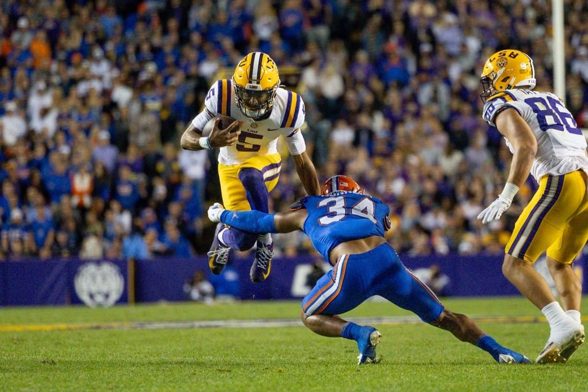 Nov 11, 2023; Baton Rouge, Louisiana, USA;  LSU Tigers quarterback Jayden Daniels (5) attempts to leap over the arms of Florida Gators linebacker Mannie Nunnery (34) during the first half at Tiger Stadium.