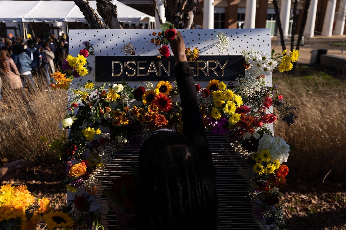 A mourner places flowers at a makeshift memorial for D’Sean Perry, one of the three victims in last November’s fatal shooting at the hands of a fellow UVA student.