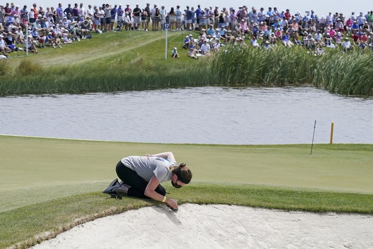 May 19, 2021; Kiawah Island, South Carolina, USA; The gallery waits as a maintenance person cleans one of the camera lens located in the bunker on 17 during a practice round for the PGA Championship golf tournament at Ocean Course at Kiawah Island Resort.