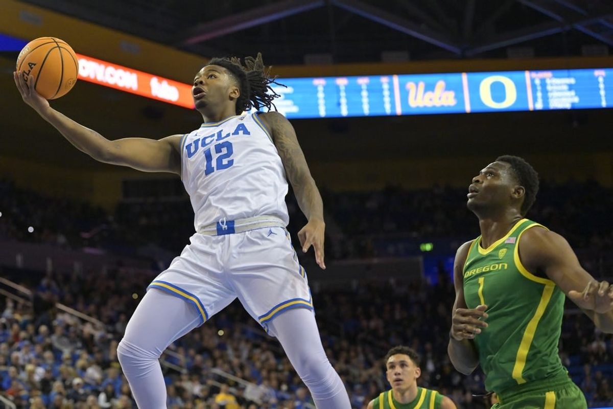 Feb 3, 2024; Los Angeles, California, USA; UCLA Bruins guard Sebastian Mack (12) drives past Oregon Ducks center N'Faly Dante (1) for a basket in the first half at Pauley Pavilion presented by Wescom.