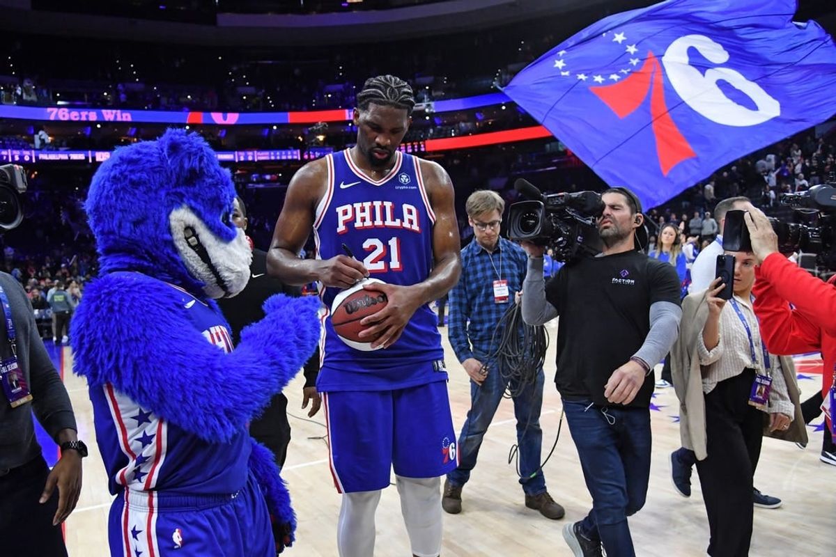 Apr 2, 2024; Philadelphia, Pennsylvania, USA; Philadelphia 76ers center Joel Embiid (21) autographs a basketball as he celebrates win against the Oklahoma City Thunder at Wells Fargo Center.