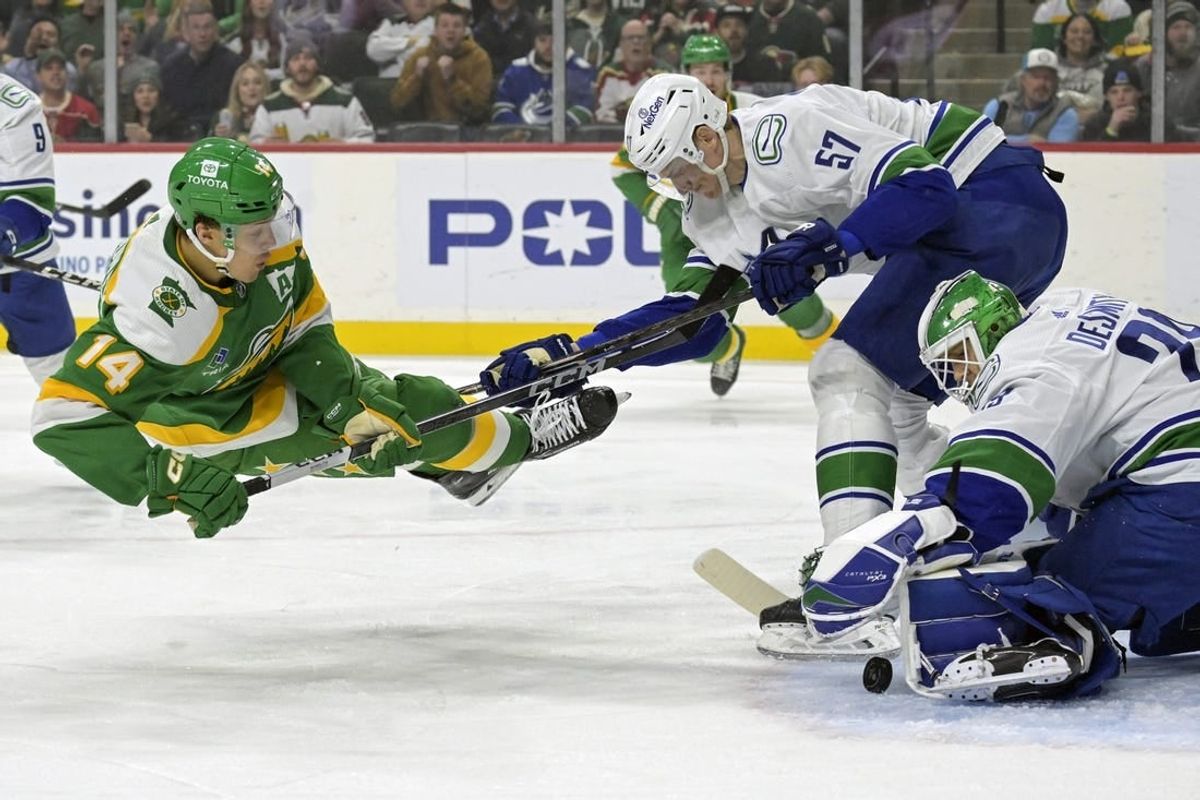 Dec 16, 2023; Saint Paul, Minnesota, USA;  Vancouver Canucks defenseman Tyler Myers (57) sends Minnesota Wild forward Joel Eriksson Ek (14) flying as goalie Casey DeSmith (29) covers the puck during the first period at Xcel Energy Center.