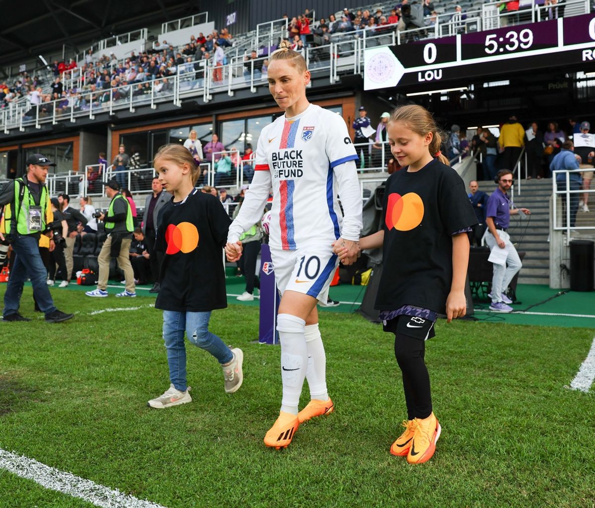 Apr 29, 2023; Louisville, Kentucky, USA;  OL Reign midfielder Jess Fishlock (10) and player escorts in a MasterCard t-shirt walk onto the pitch before the game against Racing Louisville FC at Lynn Family Stadium. Mandatory Credit: EM Dash-Imagn Images