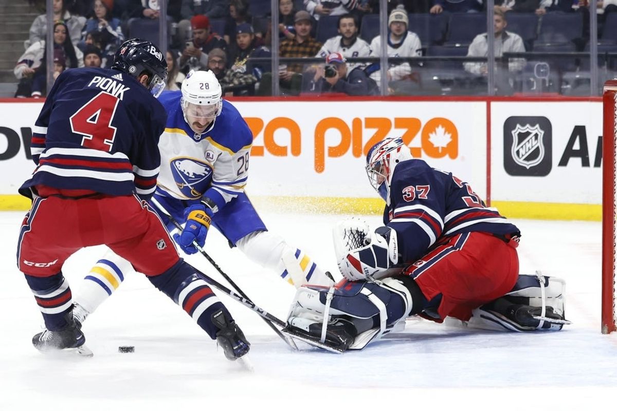 Nov 17, 2023; Winnipeg, Manitoba, CAN; Winnipeg Jets defenseman Neal Pionk (4) and Buffalo Sabres left wing Zemgus Girgensons (28) scramble for a rebound in front of Winnipeg Jets goaltender Connor Hellebuyck (37) in the first period at Canada Life Centre.