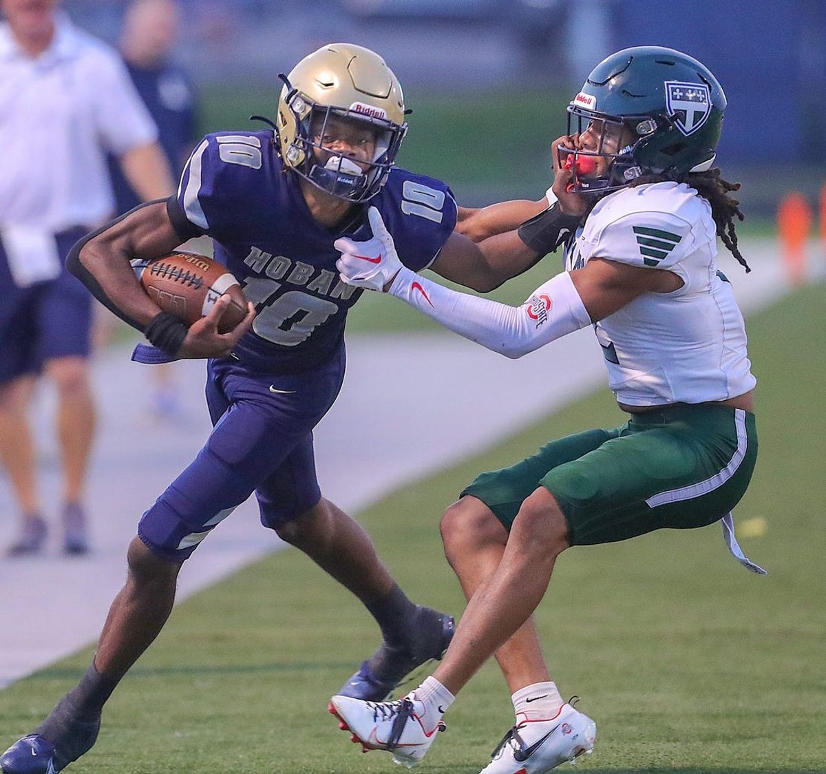 Hoban quarterback Tylan Boykin fends off Trinity Episcopal School defensive back Deuce Edwards on Saturday, Sept. 2, 2023, in Akron, Ohio, at Dowed Field.