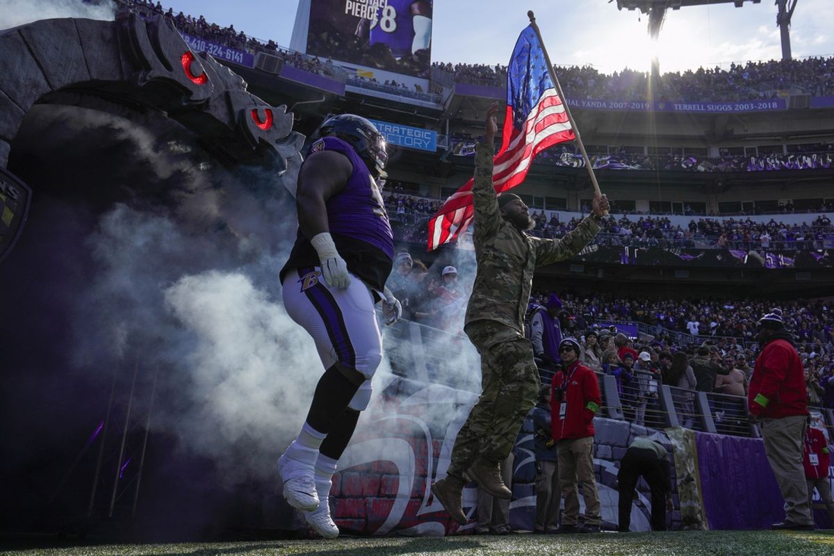 Nov 12, 2023; Baltimore, Maryland, USA;  Baltimore Ravens defensive tackle Michael Pierce (58) takes the field with a military service member before a game against the Cleveland Browns at M&T Bank Stadium. Mandatory Credit: Jessica Rapfogel-Imagn Images