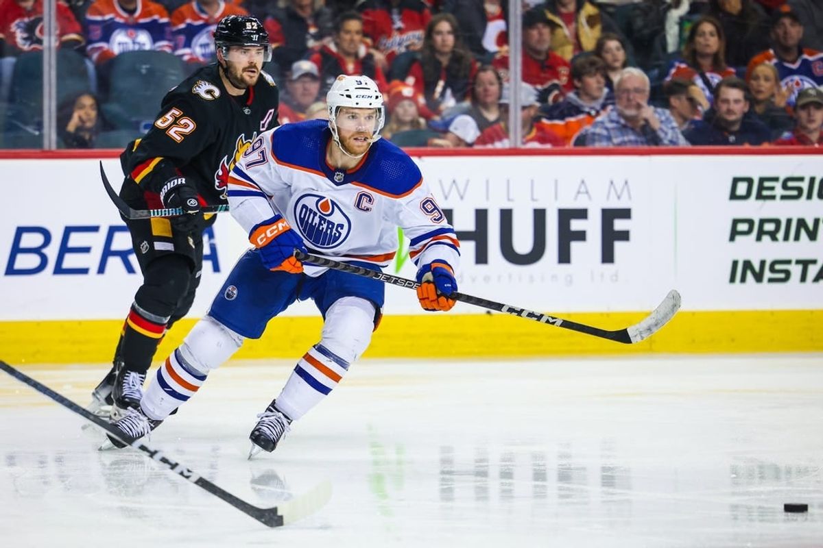 Apr 6, 2024; Calgary, Alberta, CAN; Edmonton Oilers center Connor McDavid (97) passes the puck against the Calgary Flames during the third period at Scotiabank Saddledome.