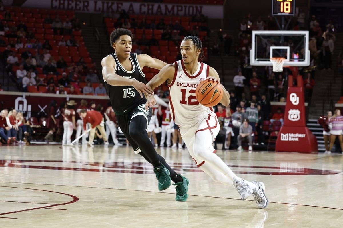 Dec 16, 2023; Norman, Oklahoma, USA; Oklahoma Sooners guard Milos Uzan (12) drives around Green Bay Phoenix guard David Douglas Jr. (15) during the second half at Lloyd Noble Center. Mandatory Credit: Alonzo Adams-USA TODAY Sports