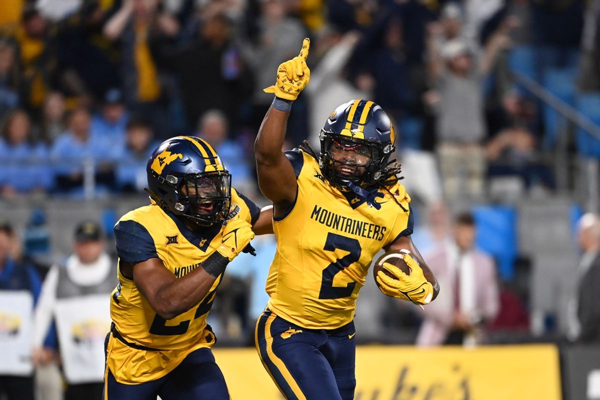 Dec 27, 2023; Charlotte, NC, USA; West Virginia Mountaineers safety Aubrey Burks (2) celebrates with safety Marcis Floyd (24) after intercepting the ball in the end zone in the first quarter at Bank of America Stadium. Mandatory Credit: Bob Donnan-Imagn Images
