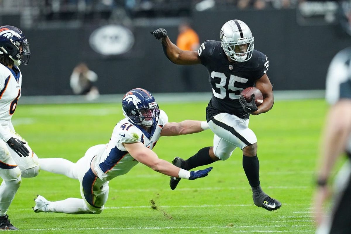 Jan 7, 2024; Paradise, Nevada, USA; Las Vegas Raiders running back Zamir White (35) is pushed out of bounds by Denver Broncos linebacker Drew Sanders (41) during the second quarter at Allegiant Stadium. Mandatory Credit: Stephen R. Sylvanie-USA TODAY Sports