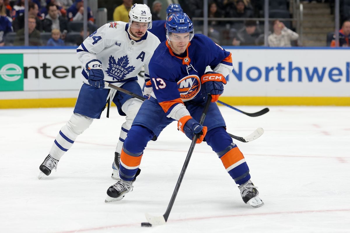 Jan 11, 2024; Elmont, New York, USA; New York Islanders center Mathew Barzal (13) skates with the puck against Toronto Maple Leafs center Auston Matthews (34) during the third period at UBS Arena. Mandatory Credit: Brad Penner-Imagn Images
