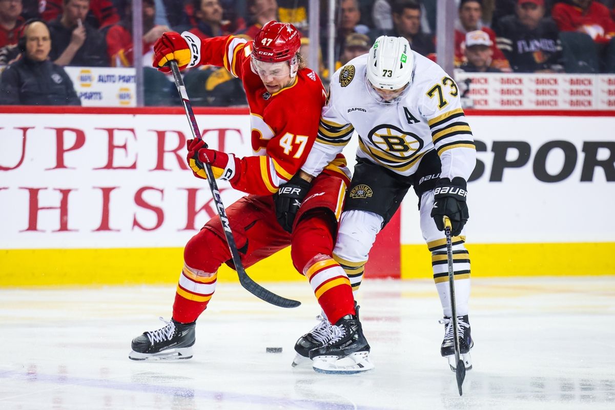 Feb 22, 2024; Calgary, Alberta, CAN; Calgary Flames center Connor Zary (47) and Boston Bruins defenseman Charlie McAvoy (73) battles for the puck during the third period at Scotiabank Saddledome. Mandatory Credit: Sergei Belski-Imagn Images