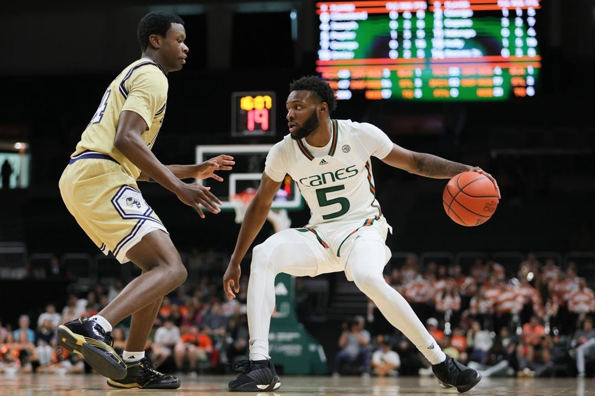 Feb 24, 2024; Coral Gables, Florida, USA; Miami Hurricanes guard Wooga Poplar (5) dribbles the basketball as Georgia Tech Yellow Jackets guard Kowacie Reeves Jr. (14) defends during the second half at Watsco Center. Mandatory Credit: Sam Navarro-USA TODAY Sports