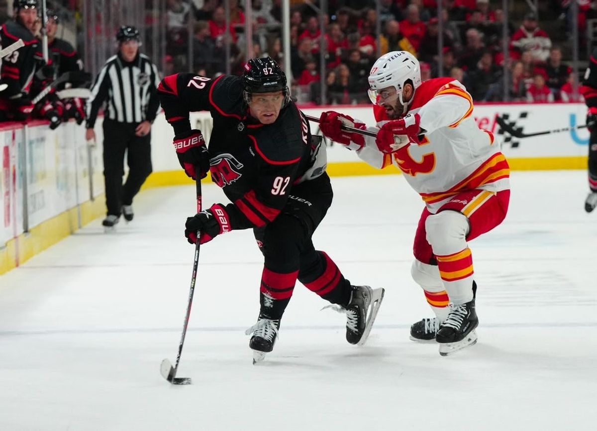 Mar 10, 2024; Raleigh, North Carolina, USA;  Carolina Hurricanes center Evgeny Kuznetsov (92) tries to control the puck against Calgary Flames right wing Matt Coronato (27) at PNC Arena.