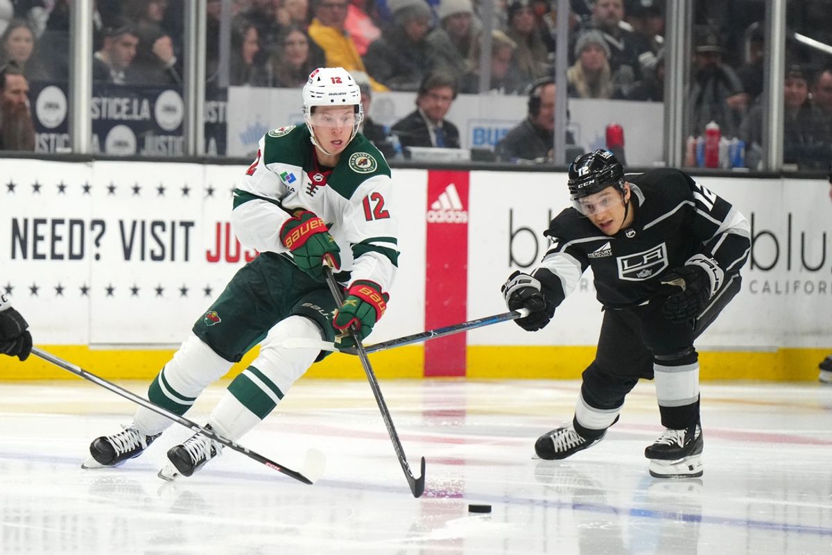 Apr 15, 2024; Los Angeles, California, USA; Minnesota Wild left wing Matt Boldy (left) and LA Kings left wing Trevor Moore reach for the puck in the third period at Crypto.com Arena. Mandatory Credit: Kirby Lee-Imagn Images