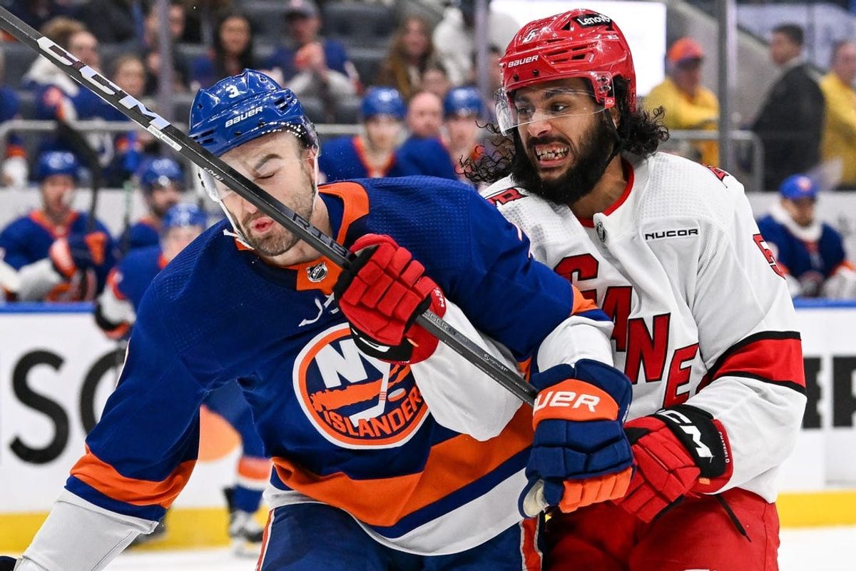Apr 25, 2024; Elmont, New York, USA;  New York Islanders defenseman Adam Pelech (3) is hit in the face with a stick by Carolina Hurricanes defenseman Jalen Chatfield (5) during the third period in game three of the first round of the 2024 Stanley Cup Playoffs at UBS Arena. Mandatory Credit: Dennis Schneidler-USA TODAY Sports
