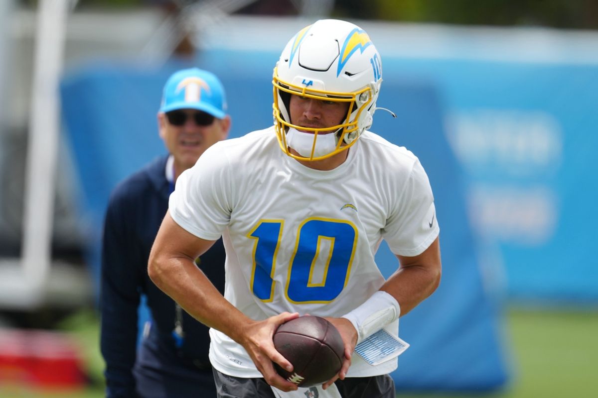 Los Angeles Chargers quarterback Justin Herbert (10) hands the ball off as coach Jim Harbaugh watches during organized team activities at the Hoag Performance Center. Mandatory Credit: Kirby Lee-Imagn Images