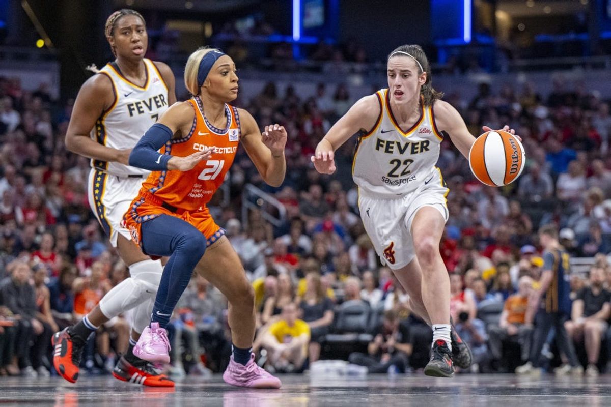 Indiana Fever guard Caitlin Clark (22) brings the ball up court while being defended by Connecticut Sun guard DiJonai Carrington (21) during the first half of an WNBA basketball game, Monday, May 20, 2024, at Gainbridge Fieldhouse.