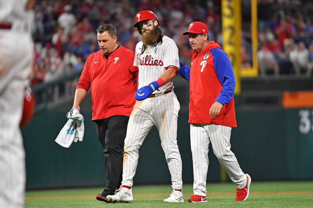 Jun 2, 2024; Philadelphia, Pennsylvania, USA; Philadelphia Phillies outfielder Brandon Marsh (16) is helped off the field by trainer Paul Buchheit and manager Rob Thomson during the eighth inning against the St. Louis Cardinals at Citizens Bank Park. Mandatory Credit: Eric Hartline-USA TODAY Sports