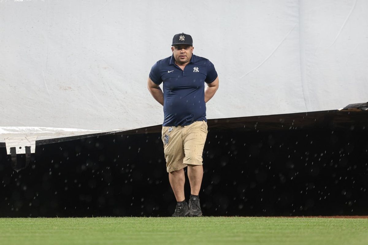 Jun 6, 2024; Bronx, New York, USA; New York Yankees grounds crew pulls the tarp on the field as rain falls at the end of the fifth inning between the Yankees and the Minnesota Twins at Yankee Stadium. Mandatory Credit: Vincent Carchietta-Imagn Images