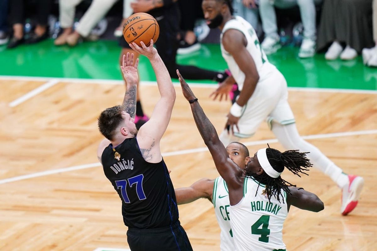 Jun 6, 2024; Boston, Massachusetts, USA; Dallas Mavericks guard Luka Doncic (77) shoots against Boston Celtics center Al Horford (42) and guard Jrue Holiday (4) in the fourth quarter during game one of the 2024 NBA Finals at TD Garden. Mandatory Credit: David Butler II-USA TODAY Sports