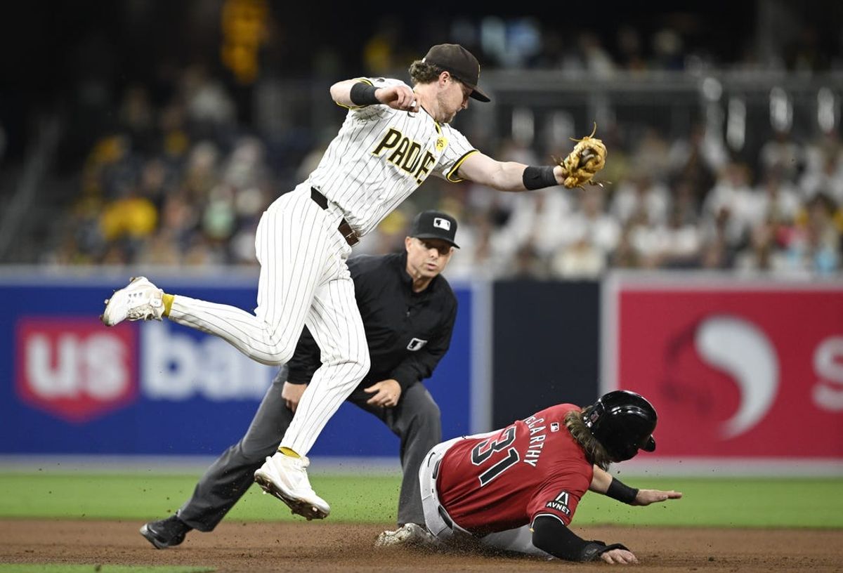 Jun 6, 2024; San Diego, California, USA; San Diego Padres first baseman Jake Cronenworth (9) fields a high throw as Arizona Diamondbacks right fielder Jake McCarthy (31) steals second base during the eighth inning at Petco Park. Mandatory Credit: Denis Poroy-USA TODAY Sports at Petco Park.