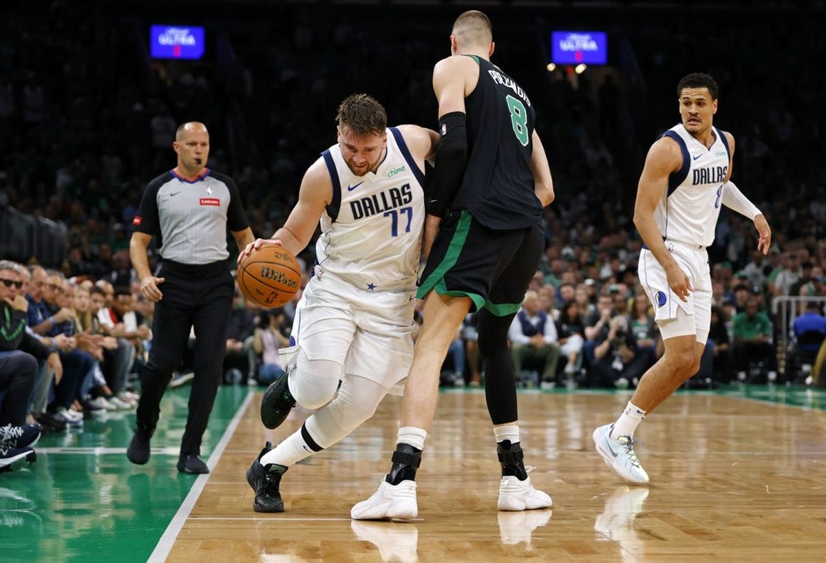 Dallas Mavericks guard Luka Doncic (77) dribbles the ball against Boston Celtics center Kristaps Porzingis (8) during the first quarter in game two of the 2024 NBA Finals at TD Garden. Mandatory Credit: Peter Casey-USA TODAY Sports
