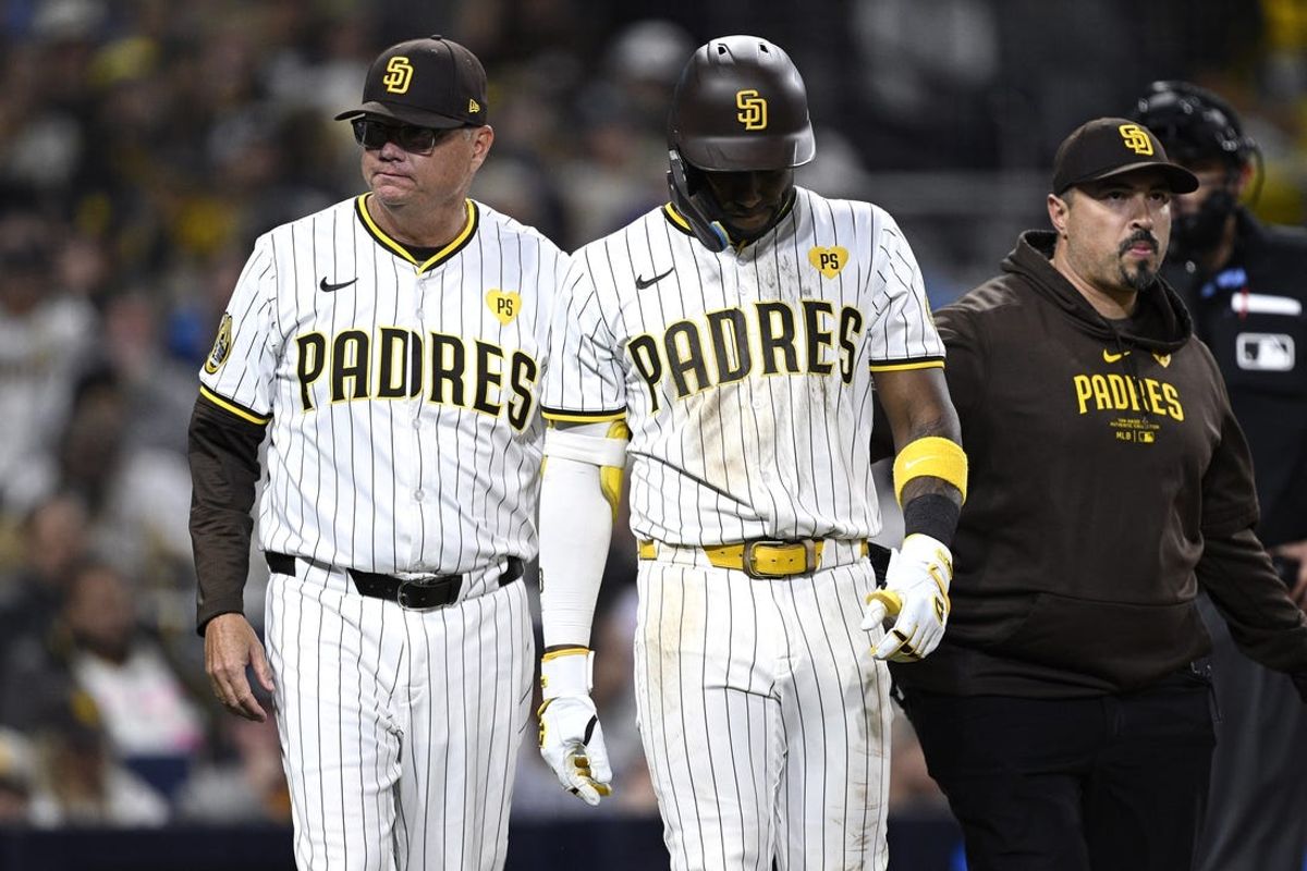 Jun 11, 2024; San Diego, California, USA; San Diego Padres left fielder Jurickson Profar (center) is helped off the field by manager Mike Shildt (left) after sustaining an injury during the eighth inning against the Oakland Athletics at Petco Park. Mandatory Credit: Orlando Ramirez-USA TODAY Sports
