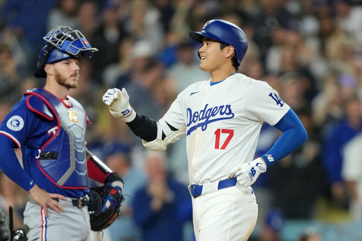 Jun 11, 2024; Los Angeles, California, USA; Los Angeles Dodgers designated hitter Shohei Ohtani (17) crosses home plate after hitting a two-run home run in the sixth inning as Texas Rangers catcher Jonah Heim (28) watches at Dodger Stadium. Mandatory Credit: Kirby Lee-USA TODAY Sports