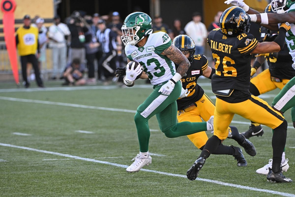 Jun 16, 2024; Hamilton, Ontario, CAN; Saskatchewan Rough Riders wide receiver Jerreth Sterns (83) carries the ball in the first quarter as Hamilton Tiger Cats defensive back Destin Talbert (26) defends at Tim Hortons Field. Mandatory Credit: Gerry Angus-Imagn Images