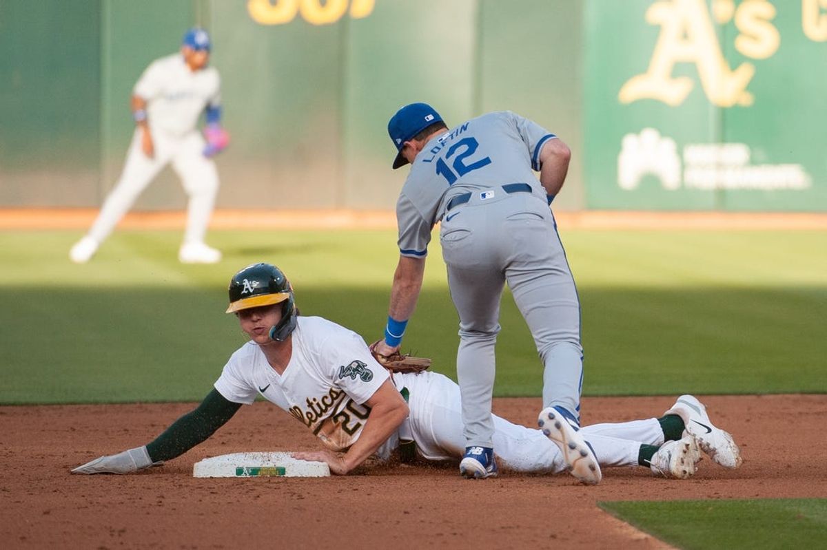 Jun 18, 2024; Oakland, California, USA; Kansas City Royals second base Nick Loftin (12) attempts to tag out Oakland Athletics second base Zack Gelof (20) at second base during the third inning at Oakland-Alameda County Coliseum. Mandatory Credit: Ed Szczepanski-USA TODAY Sports