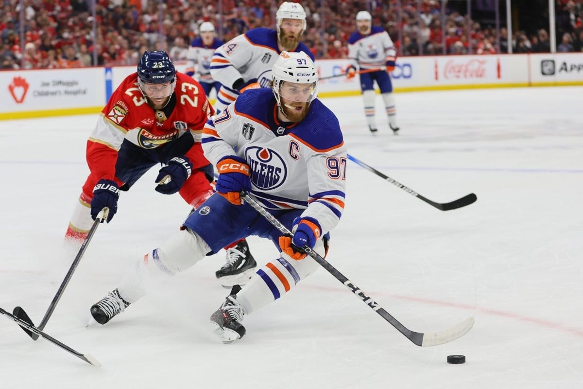 Jun 24, 2024; Sunrise, Florida, USA; Edmonton Oilers forward Connor McDavid (97) controls the puck as Florida Panthers forward Carter Verhaeghe (23) reaches to defend during the first period in game seven of the 2024 Stanley Cup Final at Amerant Bank Arena. Mandatory Credit: Sam Navarro-Imagn Images