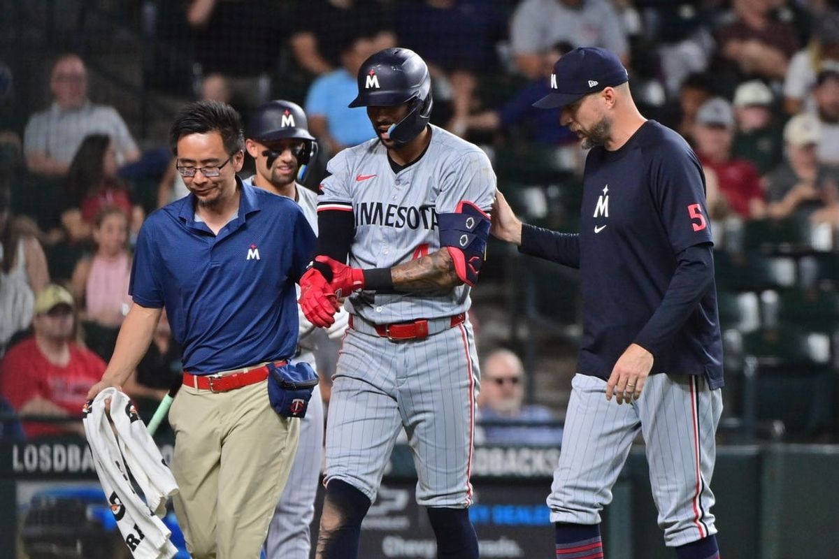 Jun 27, 2024; Phoenix, Arizona, USA;  Minnesota Twins shortstop Carlos Correa (4) leaves the field with manager Rocco Baldelli (5) and a trainer after being hit by a pitch in the seventh inning against the Arizona Diamondbacks at Chase Field. Mandatory Credit: Matt Kartozian-USA TODAY Sports