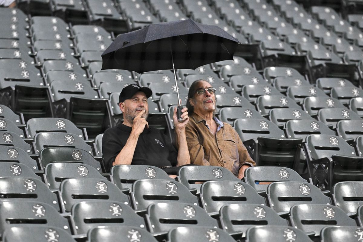 Jun 27, 2024; Chicago, Illinois, USA;  Fans sit under an umbrella as rain delayed a game between the Colorado Rockies and the Chicago White Sox at Guaranteed Rate Field. Mandatory Credit: Matt Marton-USA TODAY Sports