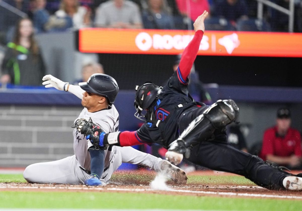 Jun 28, 2024; Toronto, Ontario, CAN; New York Yankees right fielder Juan Soto (22) slides into home plate scoring a run ahead of the tag from Toronto Blue Jays catcher Danny Jansen (9) during the fourth inning at Rogers Centre. Mandatory Credit: Nick Turchiaro-USA TODAY Sports