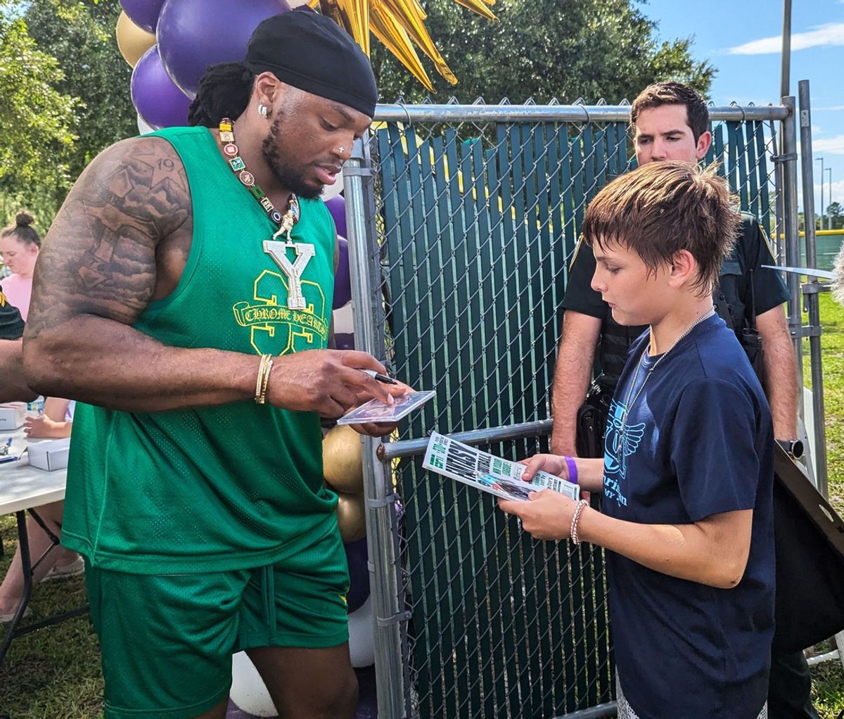 Baltimore Ravens running back Derrick Henry signs a magazine for a young fan at the Two-All Carnivall in Yulee on June 29, 2024. [Clayton Freeman/Florida Times-Union]