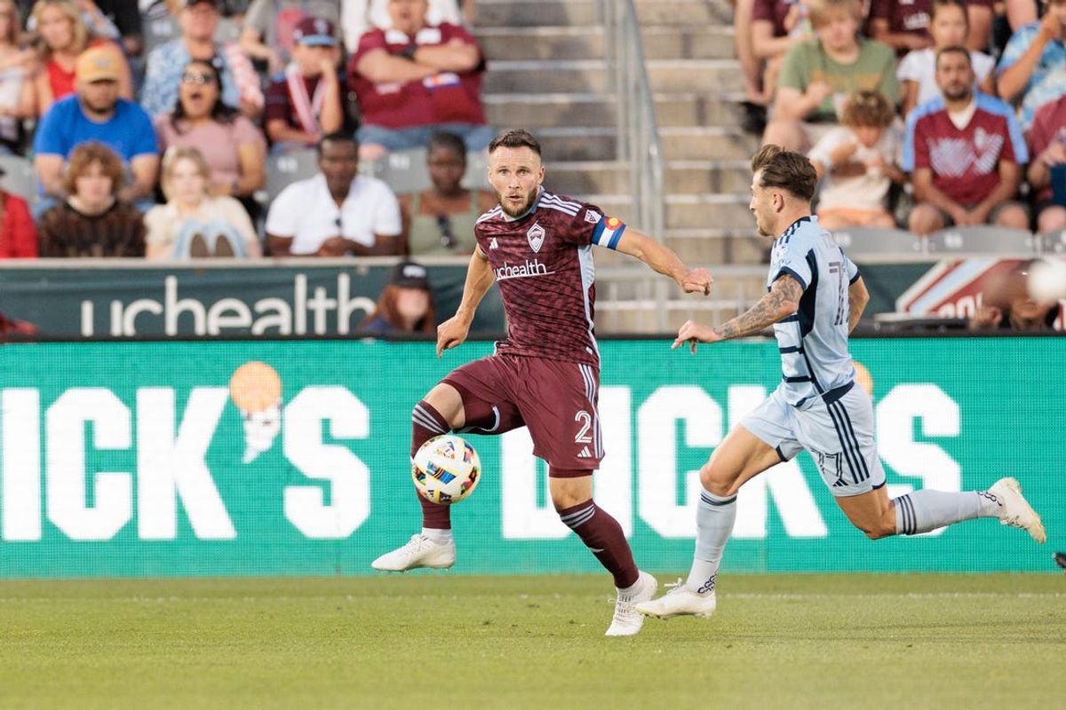 Jul 4, 2024; Commerce City, Colorado, USA; Colorado Rapids defender Keegan Rosenberry (2) runs with the ball against Sporting Kansas City forward Marinos Tzionis (77) during the first half at Dick's Sporting Goods Park. Mandatory Credit: Andrew Wevers-USA TODAY Sports
