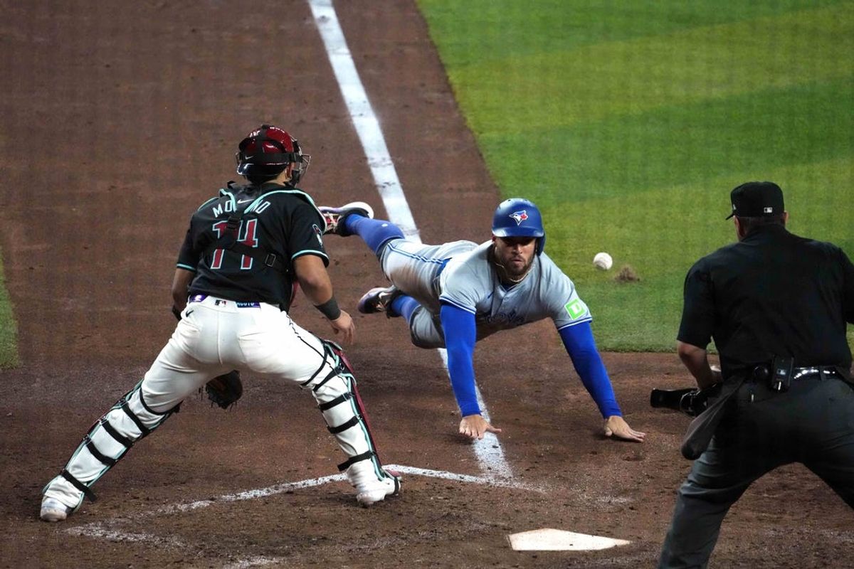 Jul 12, 2024; Phoenix, Arizona, USA; Toronto Blue Jays outfielder George Springer (4) beats a throw to Arizona Diamondbacks catcher Gabriel Moreno (14) to score a run during the sixth inning at Chase Field. Mandatory Credit: Joe Camporeale-USA TODAY Sports