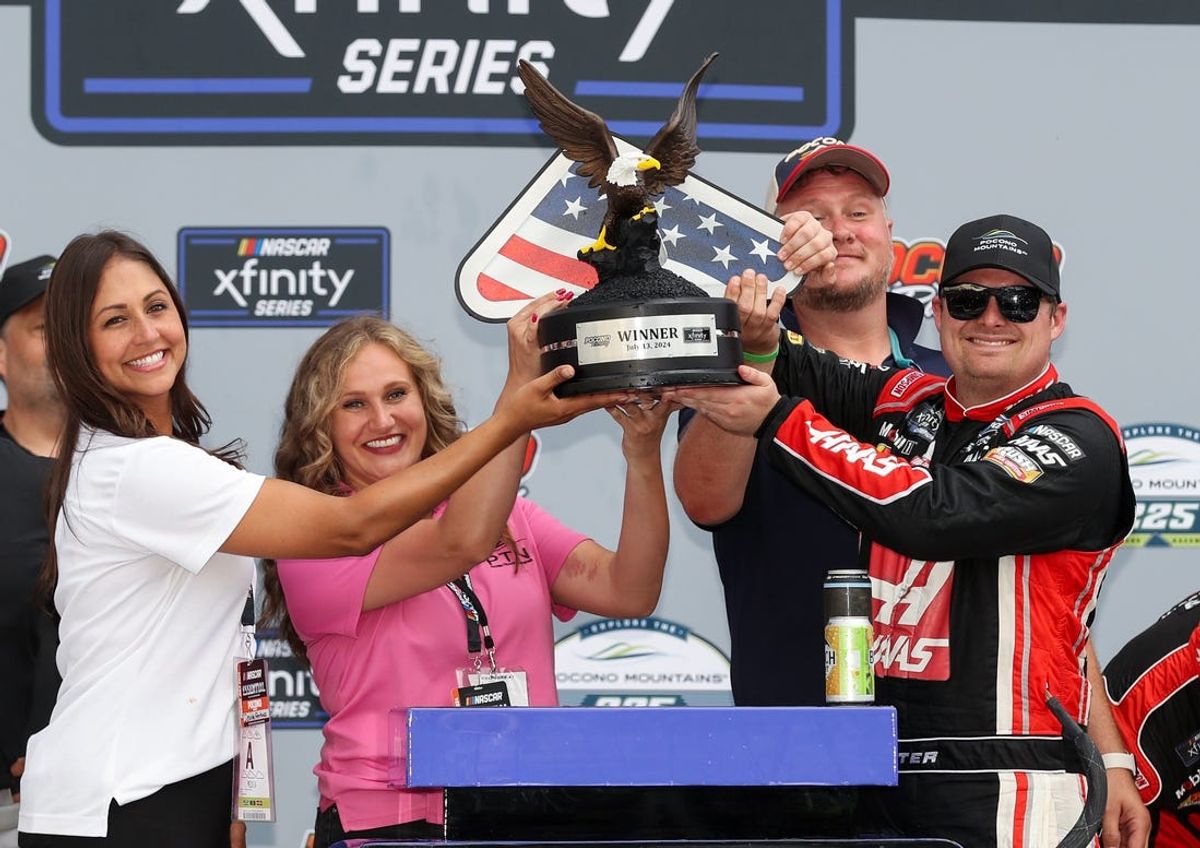 Jul 13, 2024; Long Pond, Pennsylvania, USA; NASCAR Xfinity Series driver Cole Custer raises the winner’s trophy in victory lane after winning the Explore The Pocono Mountains 225 at Pocono Raceway. Mandatory Credit: Matthew O'Haren-USA TODAY Sports