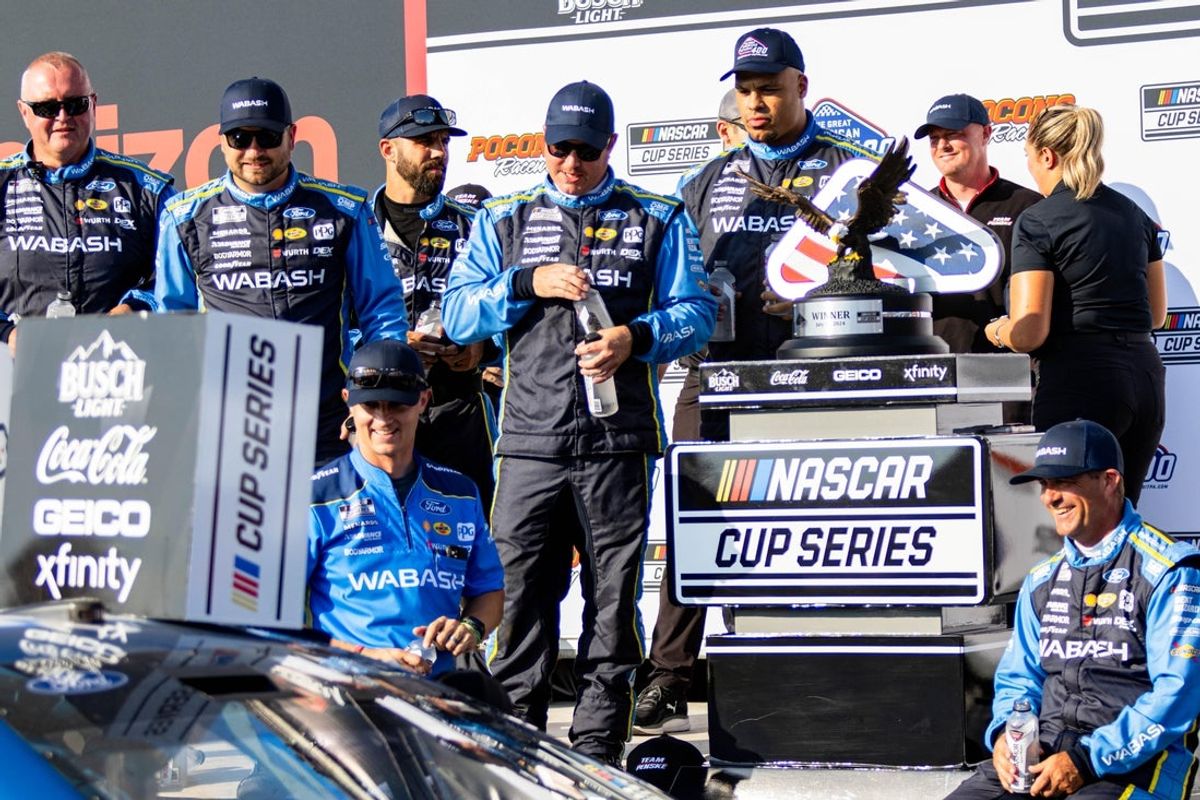 Team Penske's Ryan Blaney (12) crew waits for him to exit his car to douse him with water after his victory at The Great American Getaway at the Pocono Raceway on July 14, 2024