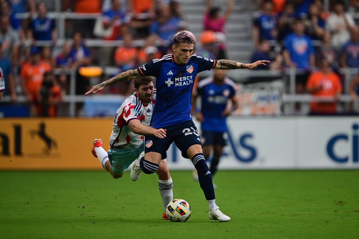 Jul 17, 2024; Cincinnati, Ohio, USA; FC Cincinnati forward Luca Orellano (23) kicks a ball in front of Chicago Fire FC midfielder Jonathan Dean (24) during the first half at TQL Stadium. Mandatory Credit: Marc Lebryk-USA TODAY Sports
