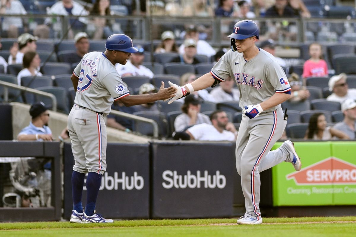 Aug 10, 2024; Bronx, New York, USA; Texas Rangers shortstop Corey Seager (5) slaps hands with Texas Rangers third base coach Tony Beasley (27) after hitting a three run home run against the New York Yankees during the sixth inning at Yankee Stadium. Mandatory Credit: John Jones-USA TODAY Sports