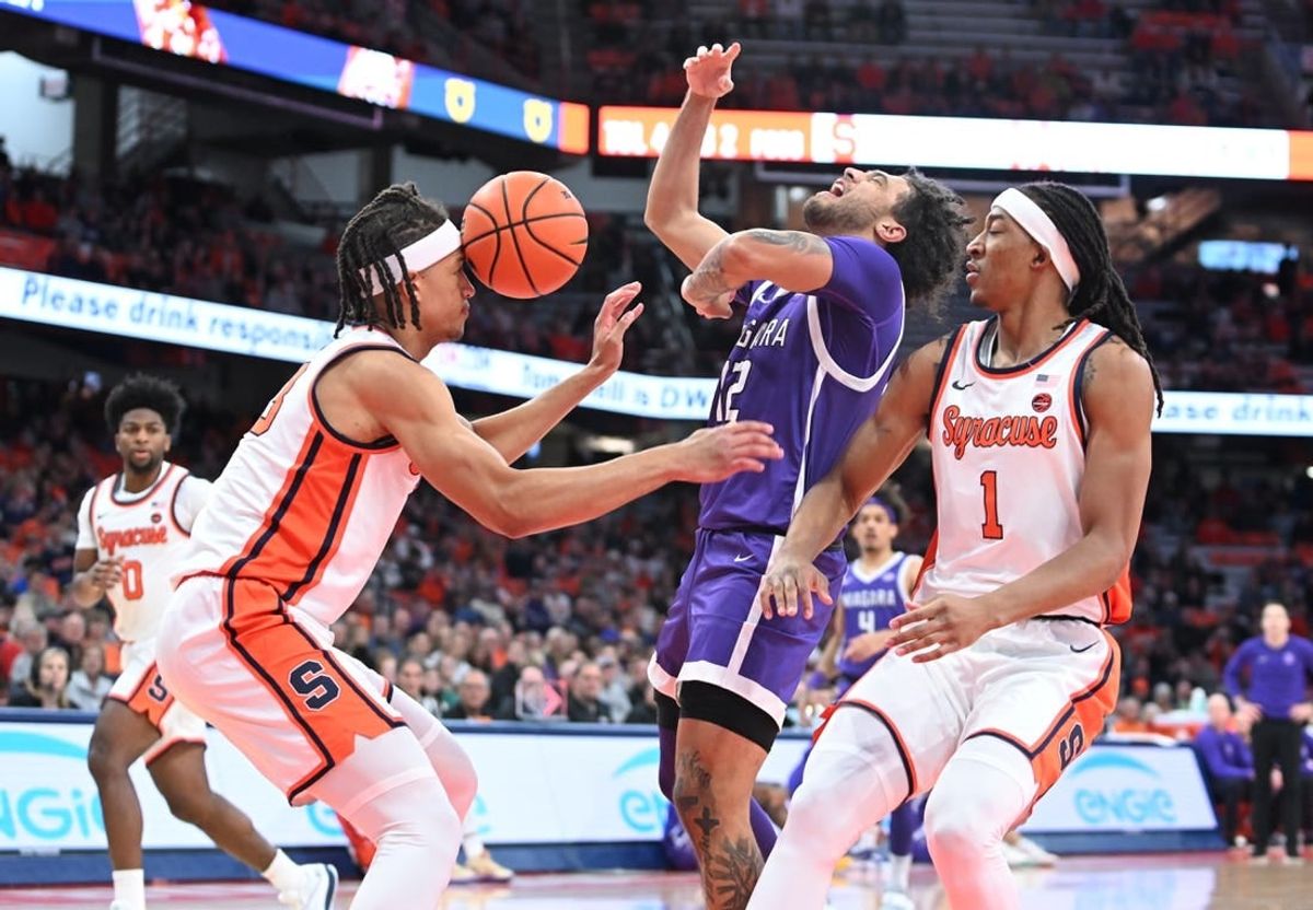 Dec 21, 2023; Syracuse, New York, USA; Syracuse Orange forward Benny Williams (13) has the ball hit his head on a drive by Niagara Purple Eagles guard Kwane Marble (12) with forward Maliq Brown (1) in the first half at the JMA Wireless Dome.