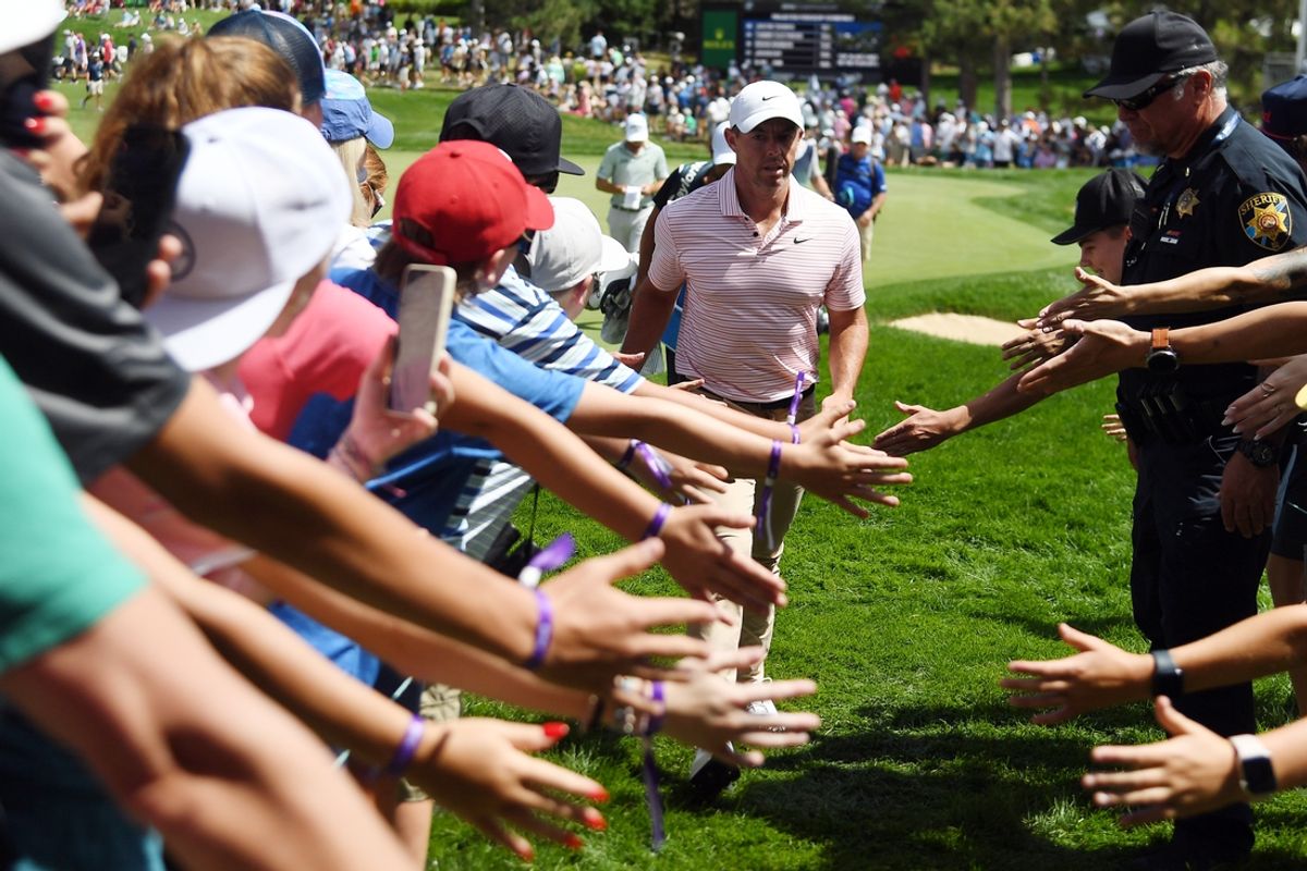 Aug 24, 2024; Castle Rock, Colorado, USA; Rory McIlroy slaps hands with fans as he leaves the 15th green during the third round of the BMW Championship golf tournament at Castle Pines Golf Club. Mandatory Credit: Christopher Hanewinckel-Imagn Images