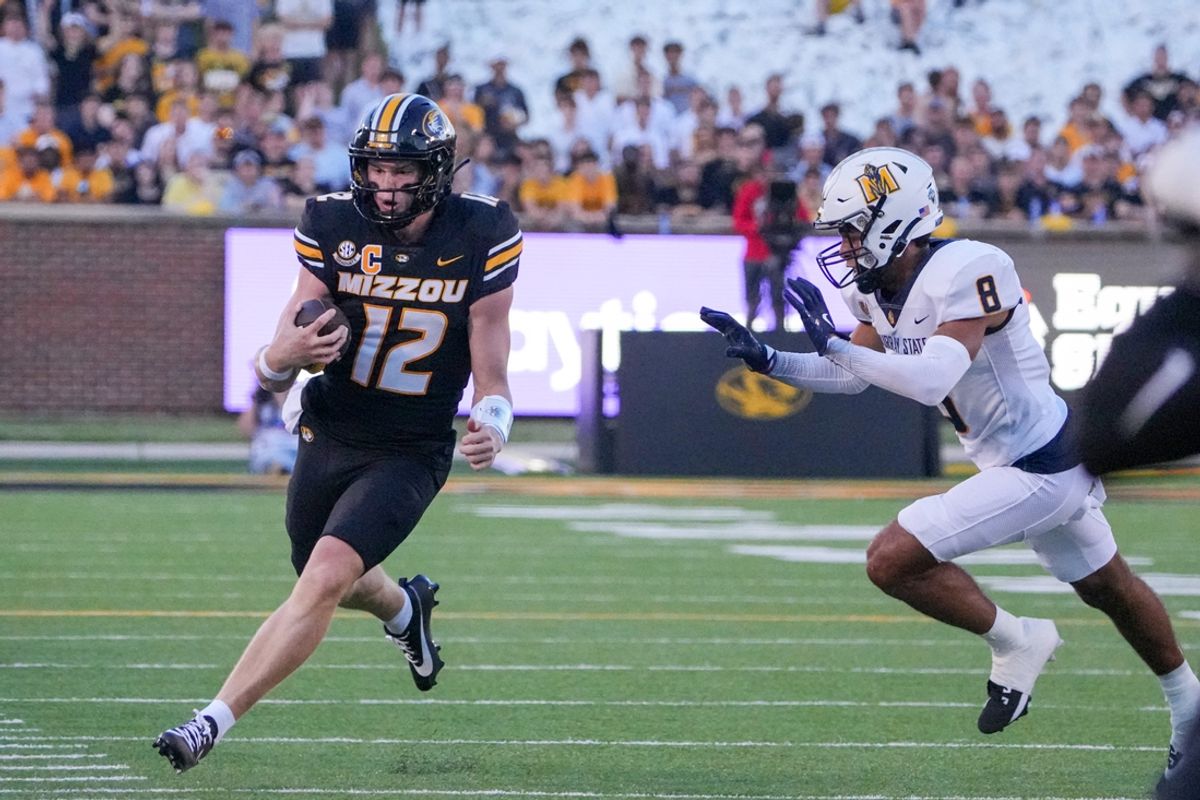 Aug 29, 2024; Columbia, Missouri, USA; Missouri Tigers quarterback Brady Cook (12) runs the ball as Murray State Racers defensive back Amari Wansley (8) chases during the first half at Faurot Field at Memorial Stadium. Mandatory Credit: Denny Medley-Imagn Images