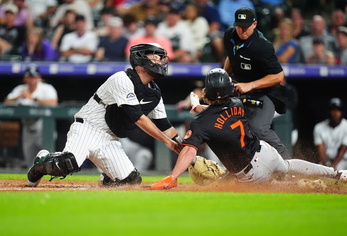 Aug 30, 2024; Denver, Colorado, USA; Baltimore Orioles second baseman Jackson Holliday (7) scores past Colorado Rockies catcher Jacob Stallings (25) in the ninth inning against the Colorado Rockies at Coors Field. Mandatory Credit: Ron Chenoy-USA TODAY Sports